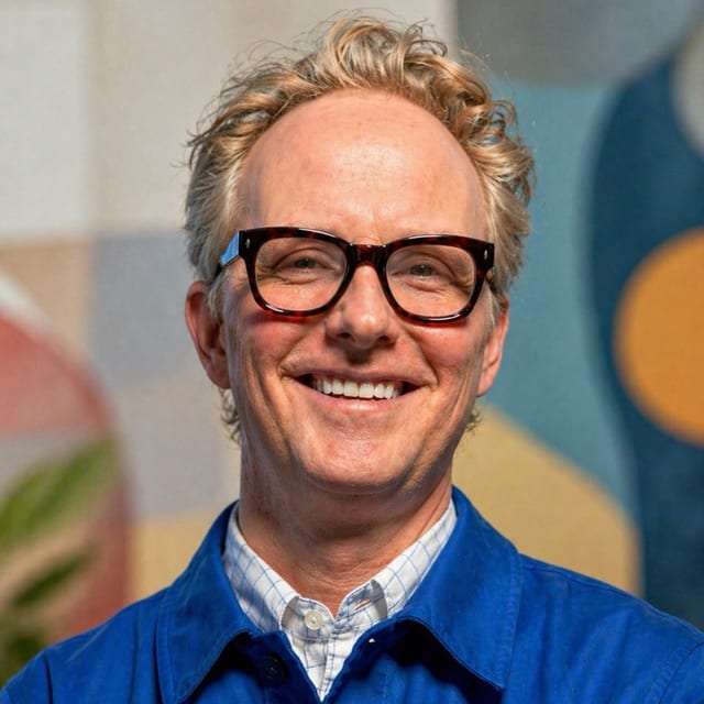 Bryan Kennedy, smiling, in glasses and a blue work jacket